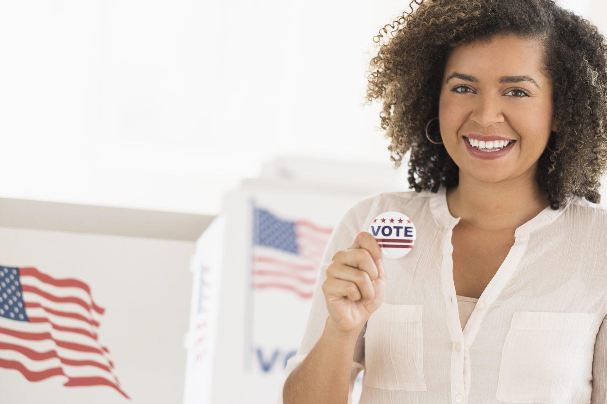 Young woman holding voting badge and smiling