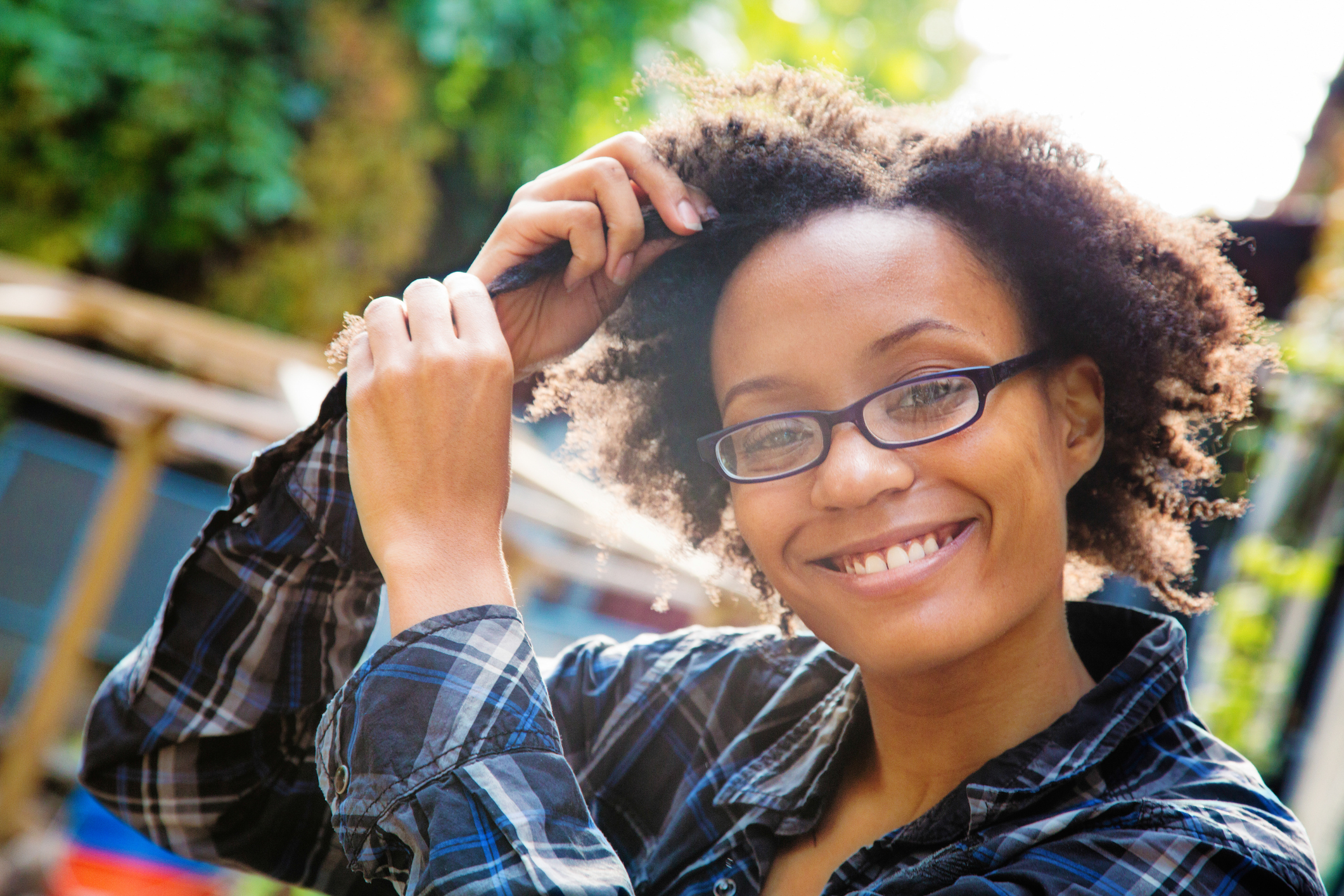 Confident happy young black woman arranging her hair outdoors