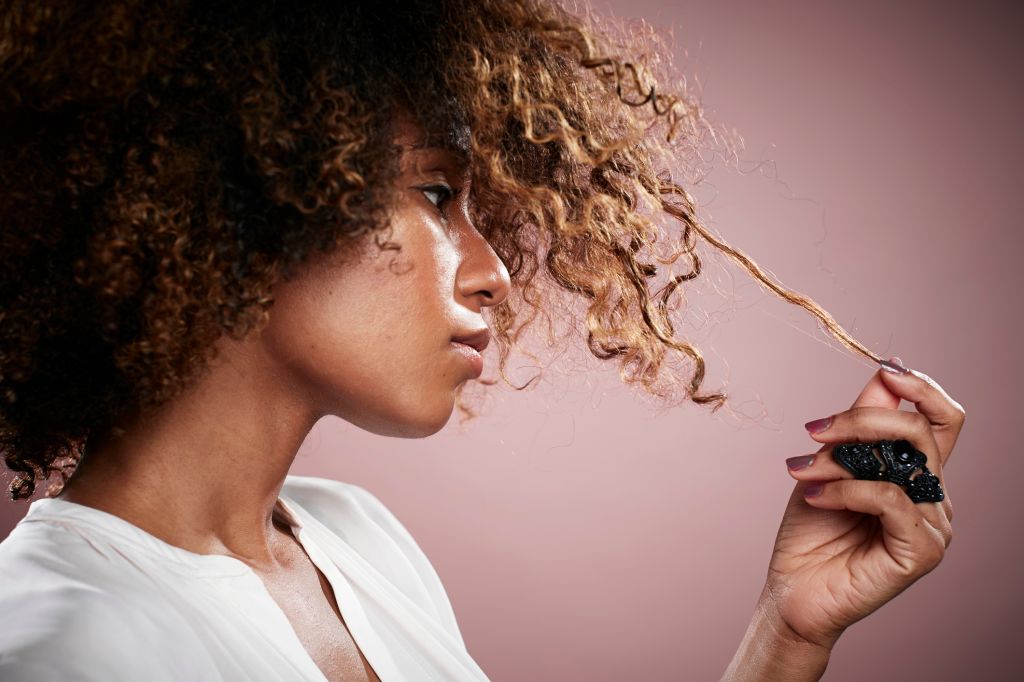 Portrait of young woman pulling on strand of curly hair