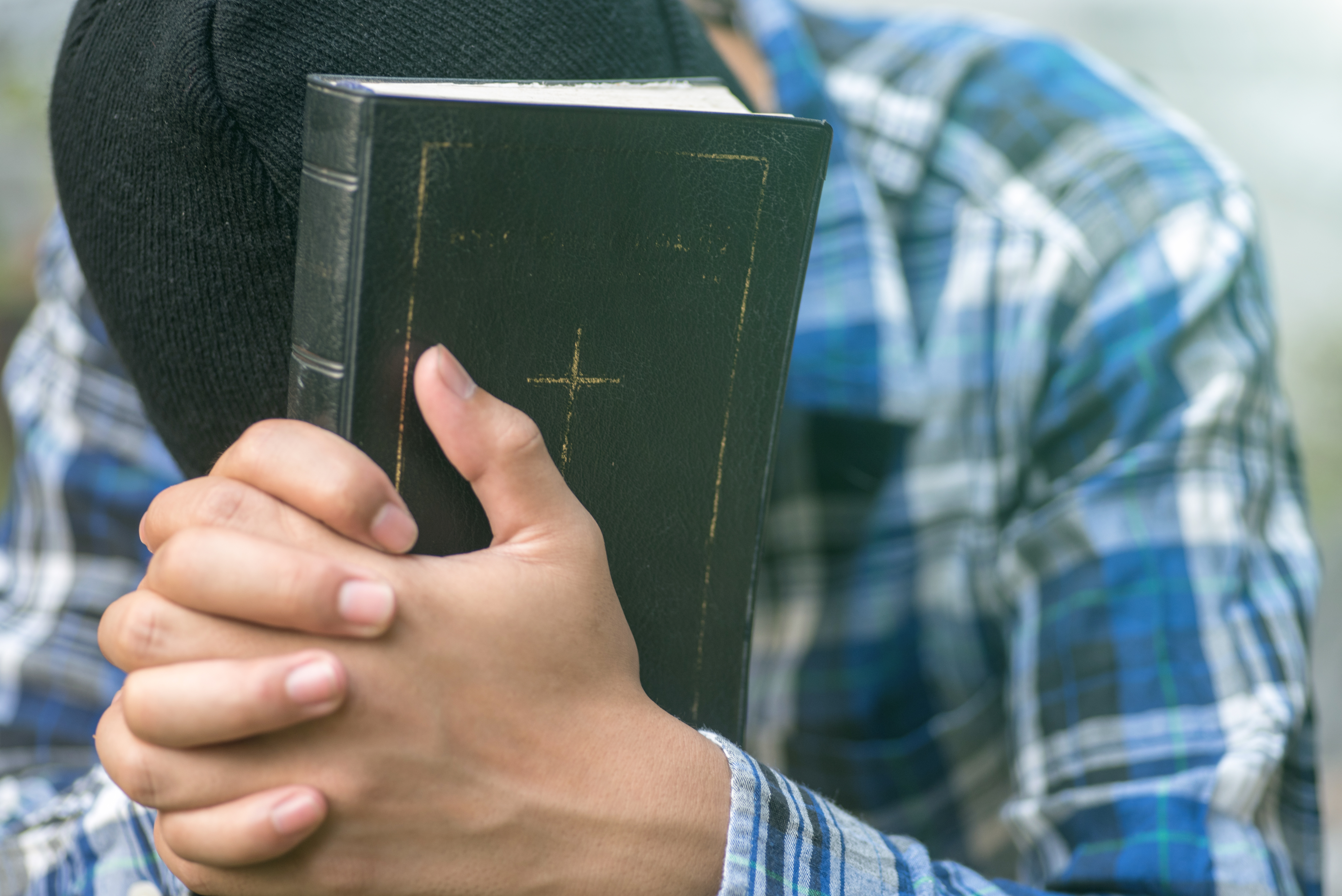 Human hand placed on the Bible, pray to God.