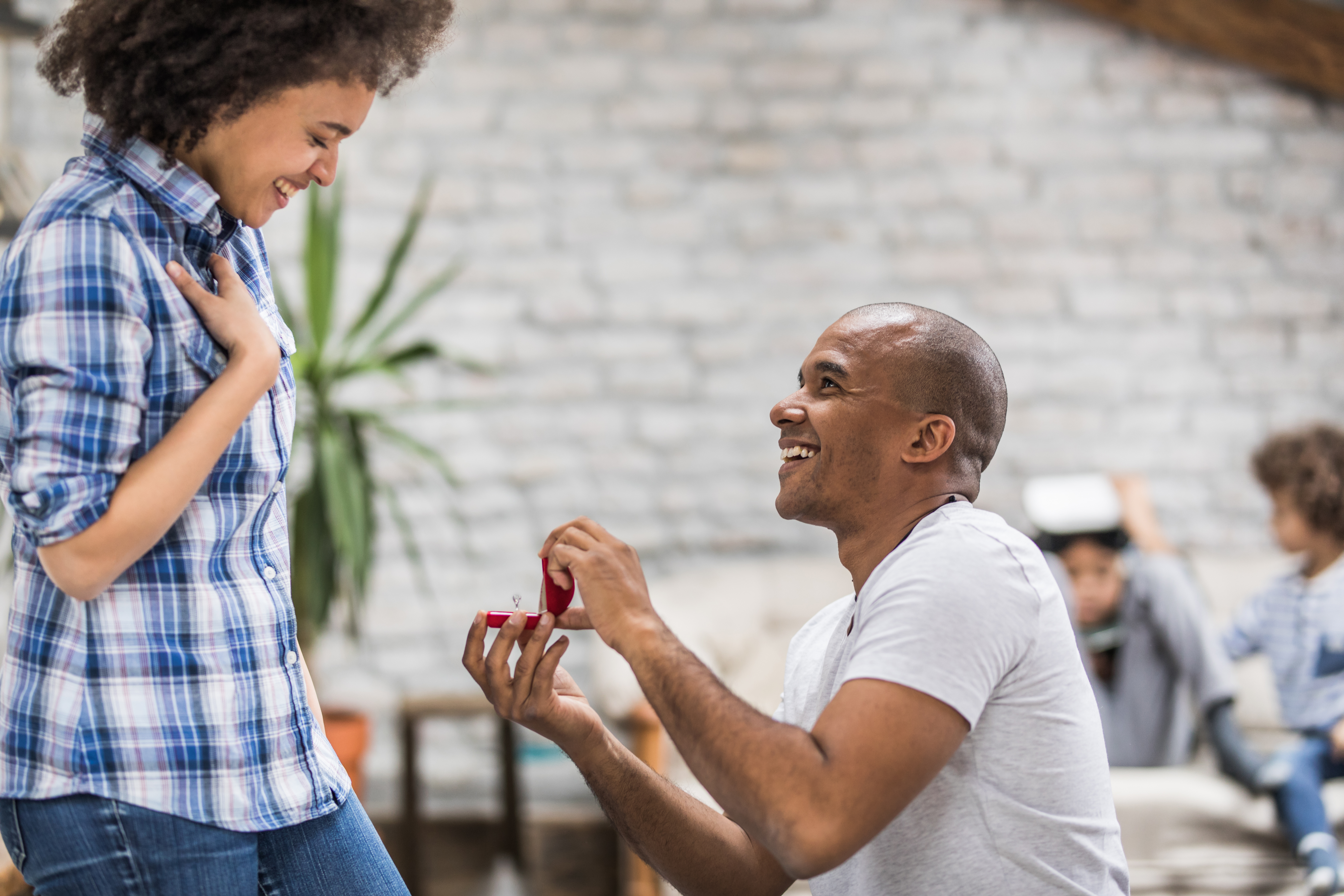 Happy African American man proposing to his girlfriend at home.