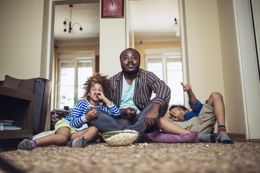 Kids watching movie with their father at home.