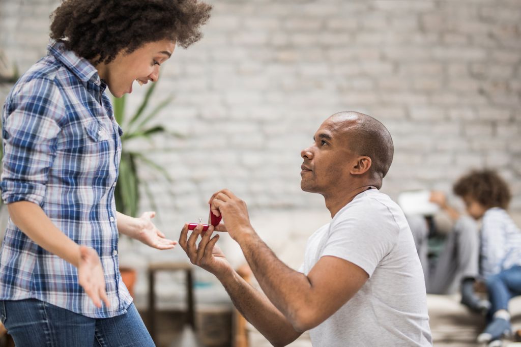 Young black man proposing to his girlfriend in the living room.