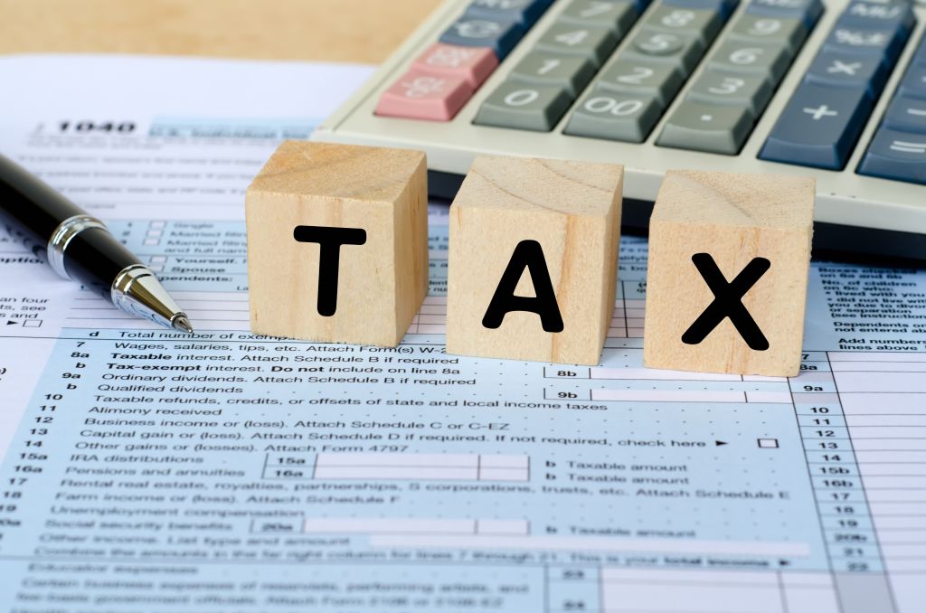 Tax Word on Wooden Block With Calculator and Tax Form