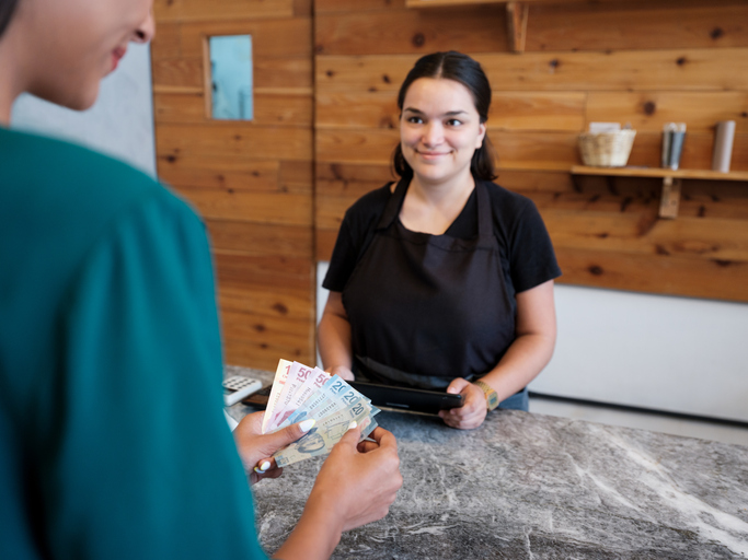 Female costumer paying in cash at counter in store