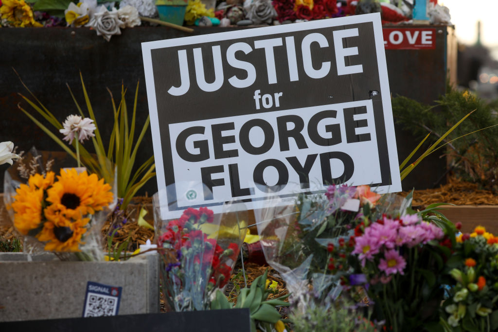 People lay flowers at a memorial in George Floyd Square...