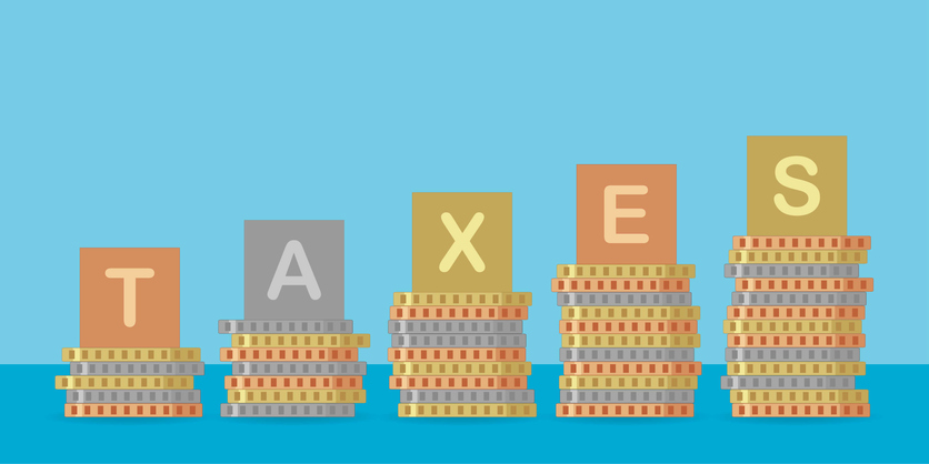Piles of coins with “taxes” text on them, taxes concept